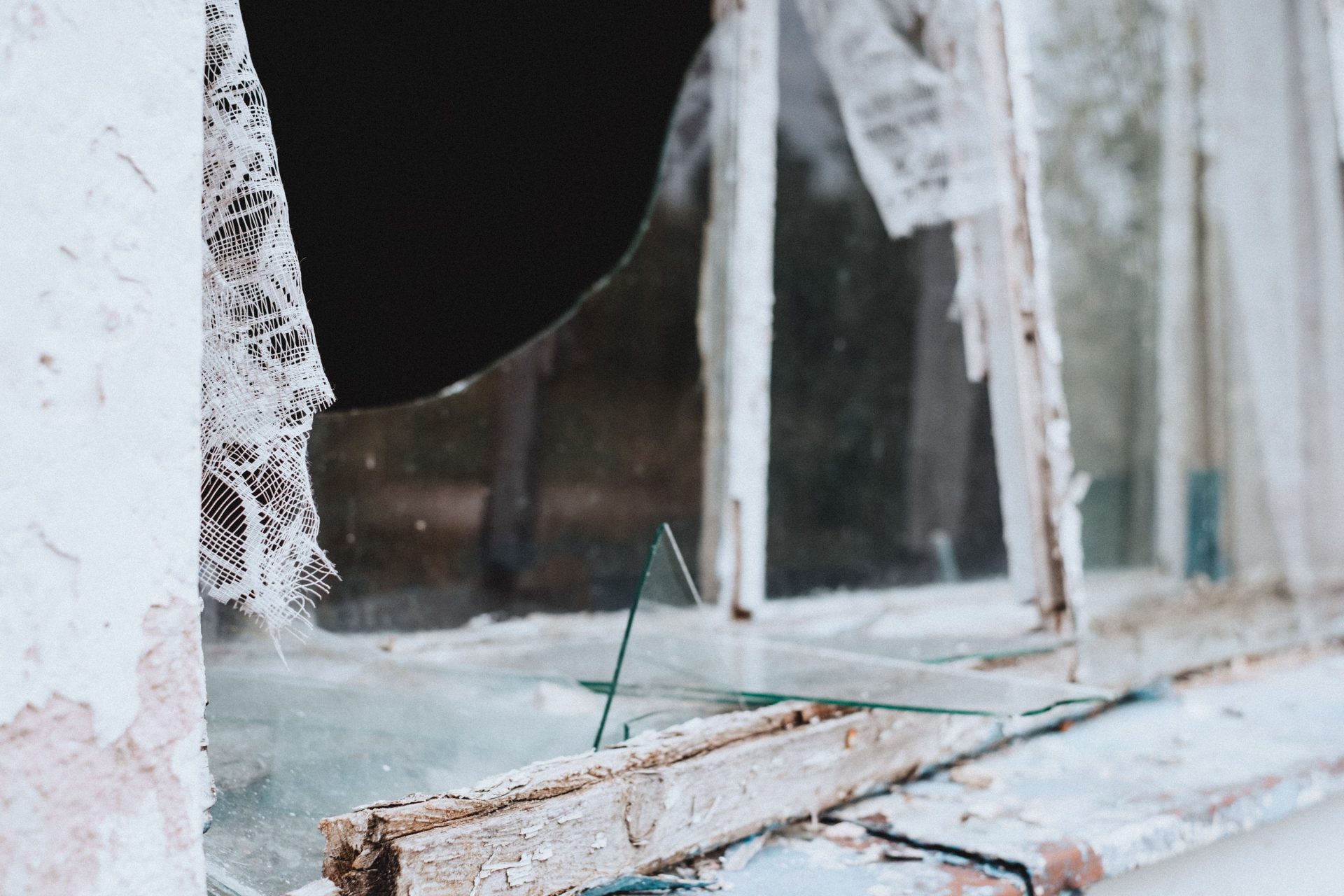 Close-up of a shattered and weathered window in an abandoned building.