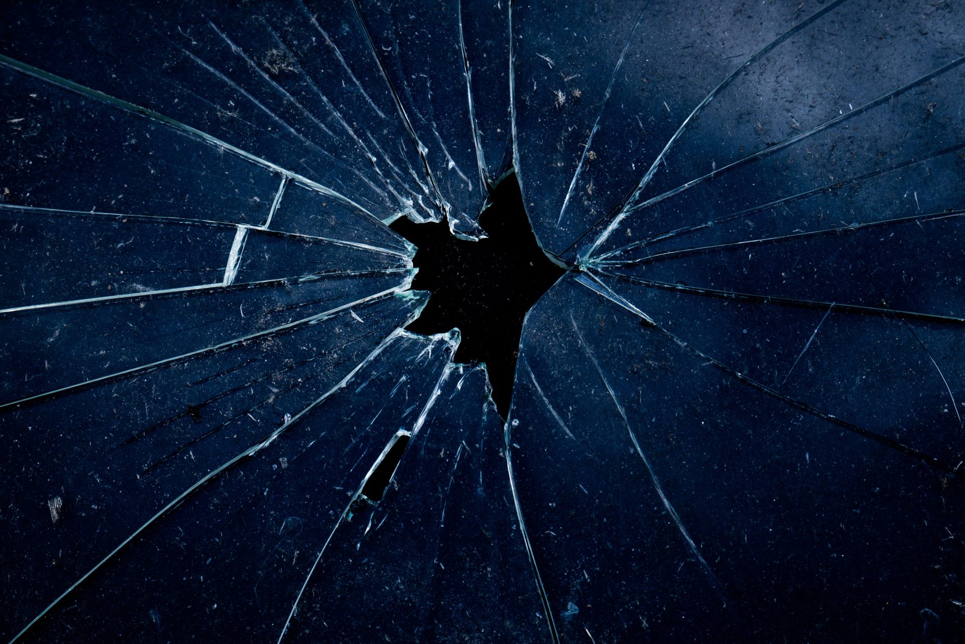 A dark blue glass surface with a central hole and radiating cracks